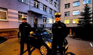 Dwóch policjantów stojących przy radiowozie.