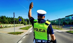 Policjant stojący tyłem z uniesiona do góry ręką