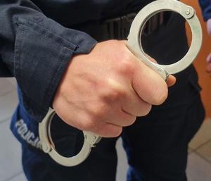 Policjant trzyma w dłoni kajdanki
